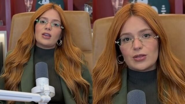 Mulher de óculos e cabelo ruivo falando ao microfone durante gravação de podcast