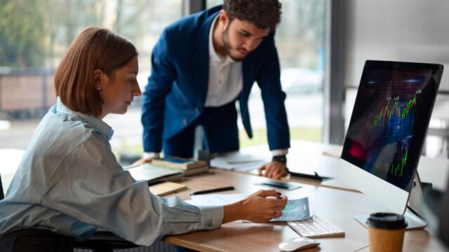 Dois profissionais analisando gráficos de desempenho no computador em escritório